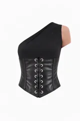Corset de un solo hombro con cuerpo superior de tela lisa y sección inferior de cuero sintético con cordones frontales ajustables mediante ojales metálicos.