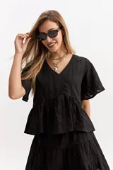 Blusa blanca de algodón con escote en V, mangas amplias y vuelo suave. Cuenta con un recorte en la cintura con frunce que aporta volumen y una caída fluida, además de una textura sutil con bordado inglés.