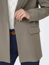 Blazer largo de corte holgado con solapas clásicas y bolsillos delanteros con solapa. Confeccionado en una mezcla de poliéster reciclado y elastano.