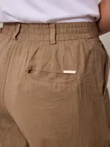 Pantalón de lino color tostado, de corte recto y tiro alto, con trabillas para cinto y bolsillos laterales.