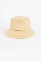 Gorro tipo bucket color beige, confeccionado en poliéster con textura de peluche.