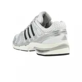 Championes Adidas Adistar Control de diseño técnico y deportivo, en color blanco con detalles plateados y las clásicas tres tiras de Adidas en negro sobre los laterales. Cuenta con una parte superior de malla transpirable, refuerzos sintéticos y una suela amortiguada de aspecto robusto.