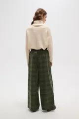 Pantalon de corte ancho y tiro alto, confeccionado en tela con estampado a cuadros en tonos verdes. Presenta cintura elástica con cordón de ajuste frontal.