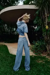 Jeans de tiro alto con pernera ancha y costuras marcadas en el frente. Presenta cintura elástica en la parte posterior, cierre frontal con cremallera y botón, bolsillos delanteros y bolsillos de plastrón en la parte trasera.