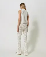 Pantalón acampanado de algodón tejido a crochet con estampado floral, bordes festoneados, cintura elástica y forro corto en contraste.