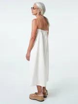 Vestido midi blanco de algodón, con cuello halter y breteles finos ajustables. Corte recto y falda acampanada.