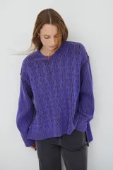 Buzo reversible de tejido de punto con diseño de trenzas, cuello redondo y mangas largas. Presenta una combinación de colores en contraste, con un lado en violeta y el otro en marrón oscuro.
