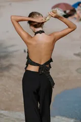 Top de cuello halter color blanco, con múltiples volantes en cascada en todo el frente y la espalda descubierta con cierre de botones y lazada en el cuello.