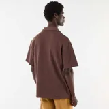 Remera de punto color marrón con cuello polo abierto y mangas cortas de corte holgado.