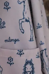 Campera de lona estampada con diseño de caballos y flores, con cuello de pana en color gris azulado y cierre frontal metálico. El interior está forrado en tela de viyela a cuadros.