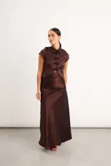 Top de tafeta elastizada con inspiración oriental, color marrón, cuello mao y cierre frontal con nudos chinos y broches. Presenta mangas cortas con detalles de puntilla negra en los bordes.