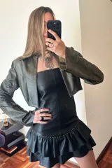 Vestido strapless de cuero ovino color negro, con volados y detalles de pequeñas piedras brillantes.