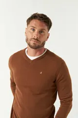 Sweater de punto color marrón, con escote en V y logo bordado en el pecho. Presenta un diseño de calce regular y mangas largas.