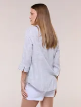 Blusa de silueta relajada con textura tramada, color azul con rayas verticales en tonos rosados, celestes y amarillos. Cuenta con cuello mao abierto en V y mangas tres cuartos amplias con pequeña abertura lateral en el puño.