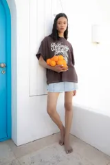 Remera blanca oversize de algodón con estampado de frutas y texto en el frente, pespuntes a contratono y tajos laterales.