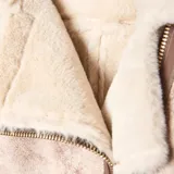 Campera estilo aviador con exterior de efecto gamuzado en tono beige y detalles en cuero sintético marrón. Cuenta con interior y solapas de piel sintética en color crema, cierre frontal cruzado y bolsillos laterales.