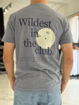 Remera gris melange de manga corta y corte clásico, con estampa en la espalda que dice "Wildest in the club" junto a un gráfico de un disco compacto.