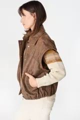 Campera de cuero estilo bomber con acabado desgastado, cuello clásico, cierre frontal oculto y mangas desmontables que permiten convertirla en chaleco.