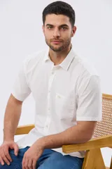 Camisa de manga corta confeccionada en mezcla de lino y algodón, color beige, con cuello camisero abotonado, bolsillo frontal en el pecho y cierre de botones.