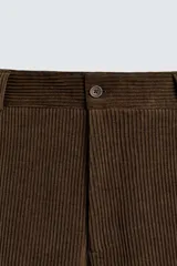 Pantalón de corte wide fit confeccionado en pana de algodón color marrón oscuro. Presenta bolsillos frontales, bolsillos traseros de vivo con botón y cierre frontal con cremallera y botón.