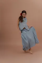 Pollera larga de lino color gris topo, de diseño amplio con volumen, movimiento y bolsillos delanteros. Cuenta con elástico en la cintura y detalles de pinzas y sobretelas en los laterales.