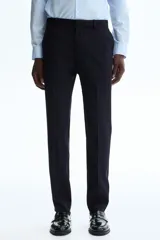 Pantalón de traje negro de corte slim fit, con bolsillos laterales, bolsillos traseros ribeteados y raya marcada en las perneras. Cuenta con cierre de cremallera y corchete oculto.