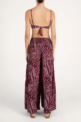 Pantalón de corte amplio con diseño de capas y cintura elástica con lazo frontal ajustable. Presenta un estampado animal print en tonos bordó y rosado.