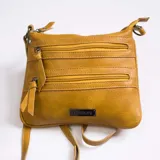 Bandolera color marrón con apertura superior de cierre metálico y dos bolsillos frontales con cierre. Incluye correa larga regulable y placa metálica con el logo de la marca.