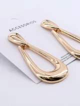 Caravanas de diseño en forma de gota, con acabado metálico brillante en tono dorado.