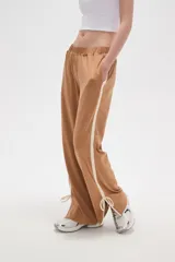Pantalon deportivo de corte recto y tiro medio, color beige oscuro. Presenta una banda lateral en tono crema y aberturas ajustables con cordones en los tobillos. Cuenta con cintura elástica.