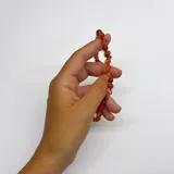 Collar de cuentas esféricas de cornalina de 6 mm, con cierre de mosquetón circular bañado en oro y detalles de nudos en hilo naranja.