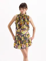 Pollera corta de viscosa gris con estampado floreado multicolor, de corte globo con volumen en el ruedo.
