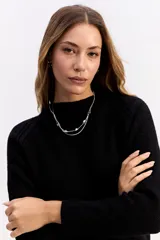 Buzo de punto negro con cuello redondo, manga larga y textura sutil. Presenta un diseño minimalista y versátil, ideal para combinar en diversas ocasiones.