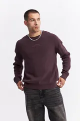 Sweater de algodón con textura acanalada, cuello redondo, mangas largas con hombros caídos y calce relajado. Presenta un logo bordado sutil en el pecho.