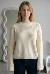 Sweater de punto en color tostado, con cuello redondo y mangas acampanadas estilo oxford. Presenta un tejido de textura acanalada y corte holgado.