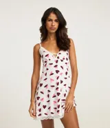 Camisón corto de microfibra color blanco con estampado de corazones en tonos rosado y bordó. Presenta breteles finos regulables, escote en V realzado con puntilla blanca y terminación de encaje en el ruedo.
