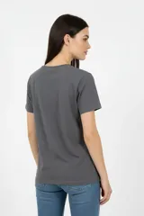 Remera de algodón color marrón topo, de corte al cuerpo y cuello a la base. Presenta un estampado frontal con diseño artístico de una figura humana con detalles en glitter.