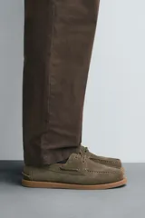 Zapato náutico color verde oliva, confeccionado en cuero serraje, con cordones de cuero y suela plana.