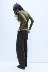 Jeans de tiro medio con diseño baggy barrel, confeccionados en denim color beige con efecto lavado. Presentan cinco bolsillos, costuras laterales torcidas y cierre frontal con cremallera y botón metálico.