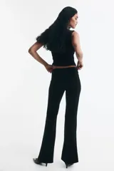 Pantalón negro de tiro alto con cierre y corchete oculto, modelo ajustado con bolsillos insertados atrás y piernas acampanadas.