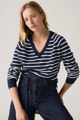 Pullover de punto con cuello en V, color azul marino con rayas horizontales blancas. Tiene mangas largas y puños acanalados.