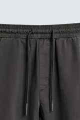 Pantalón tipo jogger de corte slim fit, confeccionado en tejido de algodón con elasticidad. Presenta cintura elástica ajustable con cordón, bolsillos frontales, bolsillos traseros de vivo y bajos con puños elásticos.