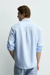 Camisa de corte regular fit confeccionada en tejido de algodón con textura twill. Presenta cuello italiano, manga larga con puños abotonados y cierre frontal de botones.