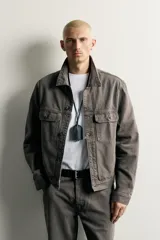 Cazadora de denim de algodón en color gris oscuro con efecto lavado, corte relaxed fit, cuello camisero, bolsillos delanteros con solapa en el pecho y cierre frontal con botones.