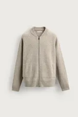 Chaqueta bomber de corte relaxed fit, tejida en hilatura de lana color beige. Cuenta con cuello subido, manga larga, bolsillos de vivo en la cadera, acabados en rib y cierre frontal de cremallera.