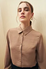 Camisa color café con textura sutil, cuello clásico, botones forrados a tono y mangas largas con puños fruncidos.