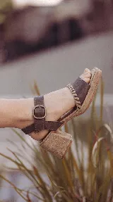 Sandalia Bruna de cuero y gamuza en tonos marrones y beige, con taco ancho, plataforma y tira al tobillo con hebilla metálica.
