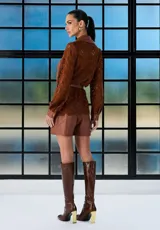 Camisa de cuero marrón con mangas de encaje al tono, cuello clásico, cierre frontal con botones y bolsillos delanteros con solapa.