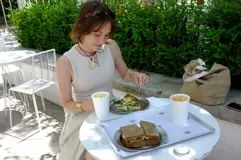 Collar con dije colgante de forma orgánica e irregular, acabado dorado, suspendido de un cordón negro de algodón natural.