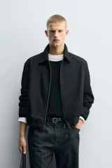 Cazadora de corte relajado confeccionada en tejido con estructura de espiga. Presenta cuello solapa, cierre frontal con cremallera, bolsillos de vivo en la cadera y bajo con pliegues en delantero y espalda.